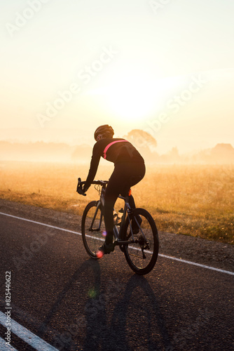 A cyclist rides along the road early in the morning photo