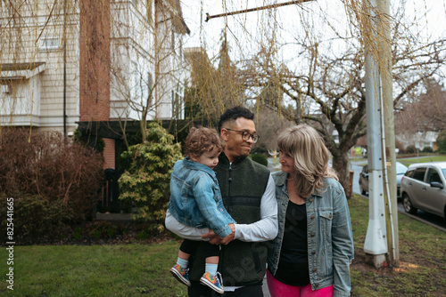 Family gathers in front of house and tree