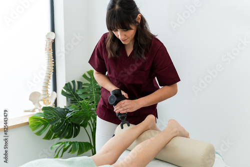 Physical therapist using percussion massager on patient's leg photo