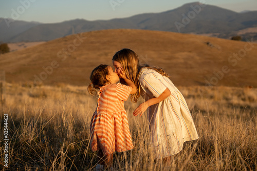 Sister kissing together at sunset on a field photo