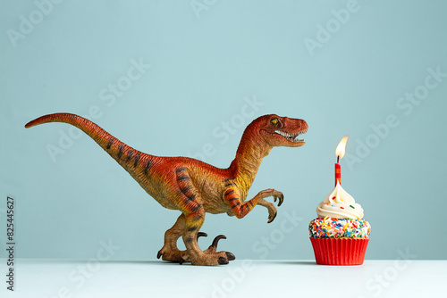 Dinosaur celebrating with a birthday cupcake photo