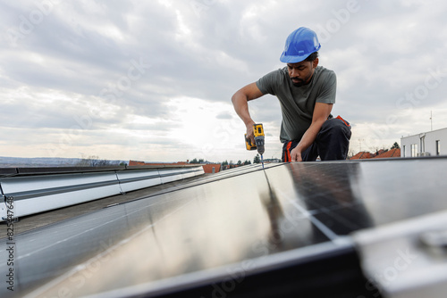 Male technician installing solar panels on rooftop photo