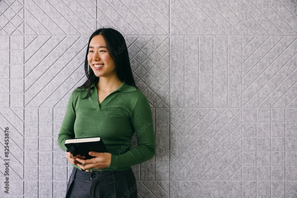 © VICTOR TORRES/Stocksy - Asian professional with planner against textured backdrop