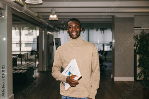 Professional man smiling with documents in an office photo