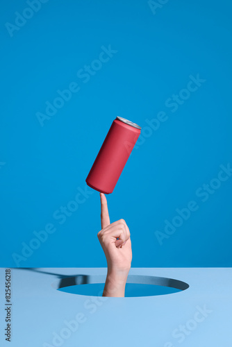 Hand through the hole on light blue background with a can balance photo