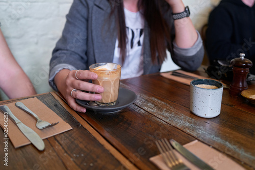 Woman's hands on latte whilst sitting in cafe photo