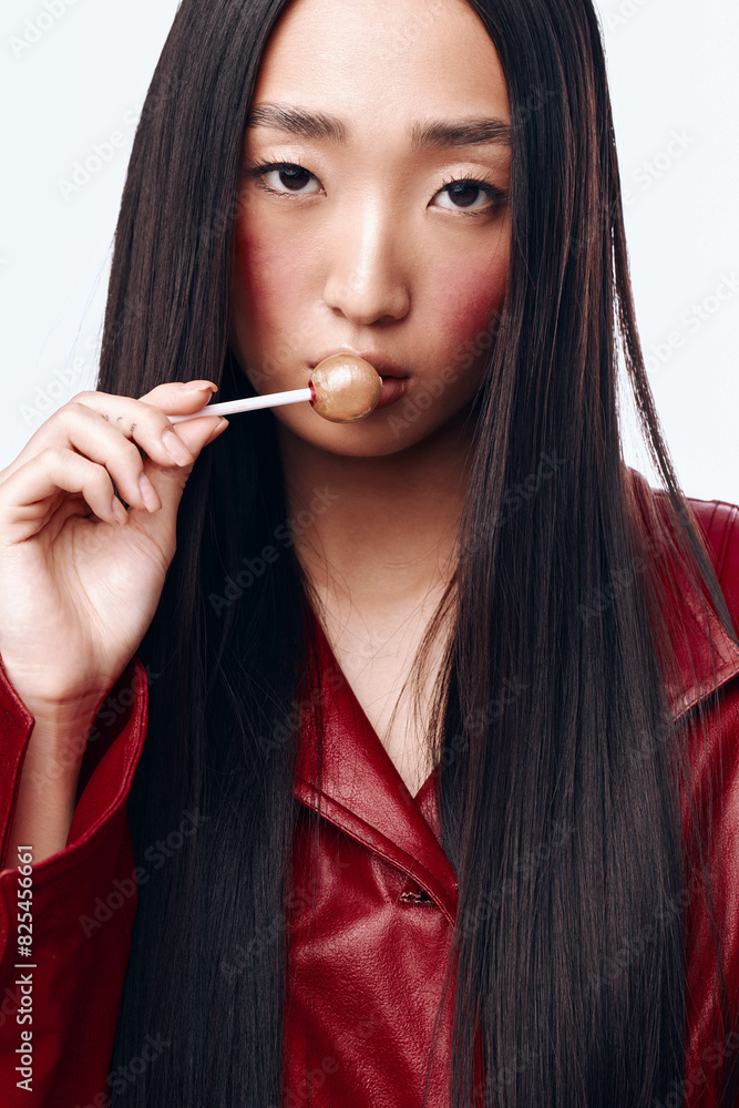 Young woman with long black hair wearing red jacket holding toothbrush in her mouth Young woman with long black hair wearing red jacket holding toothbrush in her mouth