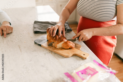 close up of pregnant woman cutting bread photo