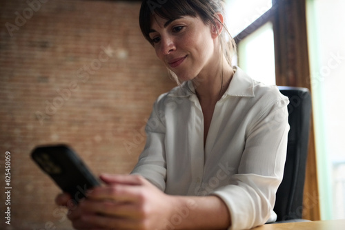 Business woman using cell phone at desk photo
