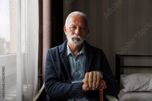 Serious senior man sitting by window photo