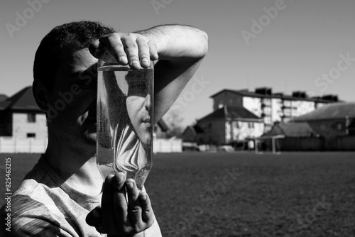 Man looking through transparent glass vase with water photo