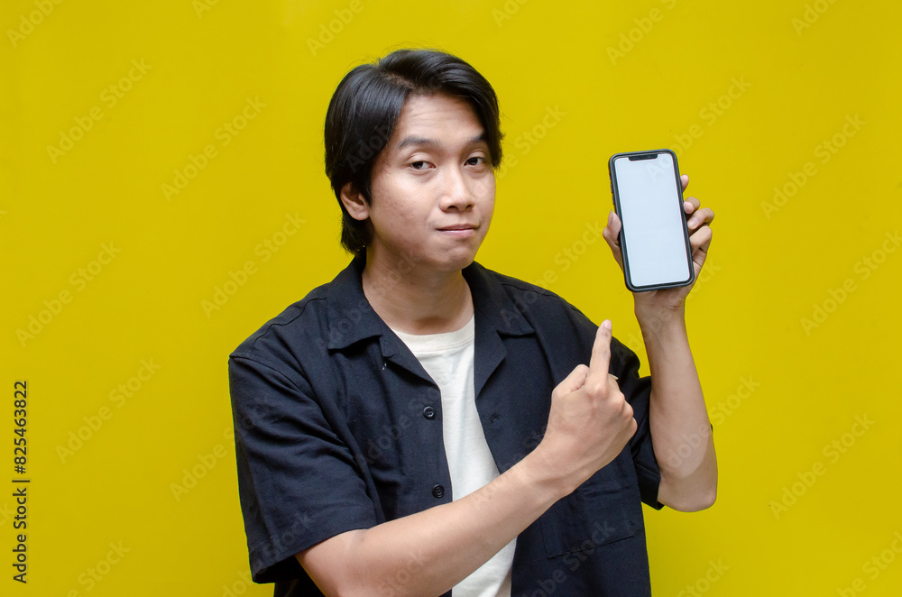 mock up young Asian man showing and pointing at blank screen smartphone. asian man in beige tshirt holding and showing phone screen with happy euphoric shocked wow expression. mock up young Asian man showing and pointing at blank screen smartphone. asian man in beige tshirt holding and showing phone screen with happy euphoric shocked wow expression.