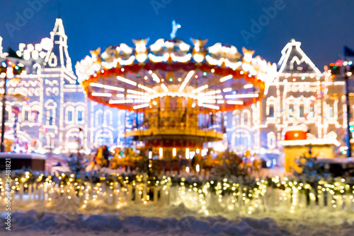 Defocused colorful merry-go-round on Christmas Fair in winter with lots of lights and bokeh on snowy evening