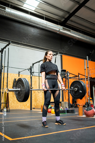 Women between 40 and 50 years old doing sports inside a gym.The middle-aged woman is working her quads with deadlifts.Concept of adult women doing sports.