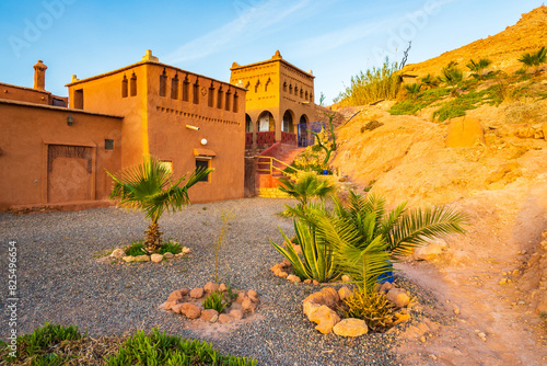 Clay buildings and gardens of traditional riad kasbah guesthouse at sunrise in Ait Ben Haddou village, Morocco, North Africa