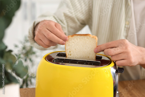Young man making crispy toasts in kitchen, closeup