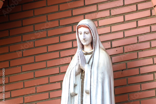 Statue of the image of Our Lady of Fátima, mother of God in the Catholic religion, Our Lady of the Rosary of Fátima, Virgin Mary with the background of a brick wall in Brazil