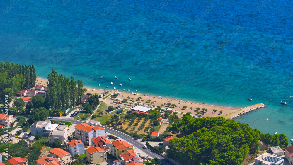 Naklejka premium AERIAL: Residential area of fun coastal town with sandy beach and colorful sea.