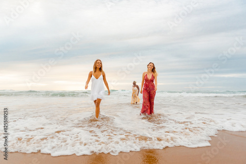 multiracial group of young women dressed in summer dresses soaking together on the seashore. Traveling with friends in summer