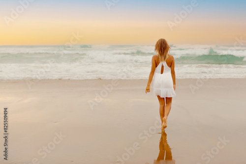 lonely girl in summer dress walking barefoot towards the sea on the beach on a summer day at sunset.