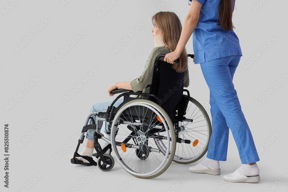 Injured young woman in wheelchair after accident with doctor on light background Injured young woman in wheelchair after accident with doctor on light background