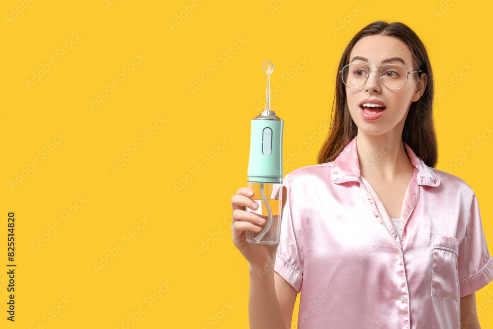 Beautiful young woman with oral irrigator on yellow background Beautiful young woman with oral irrigator on yellow background