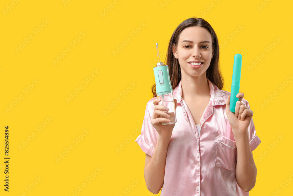 Beautiful young woman with oral irrigator and case on yellow background Beautiful young woman with oral irrigator and case on yellow background