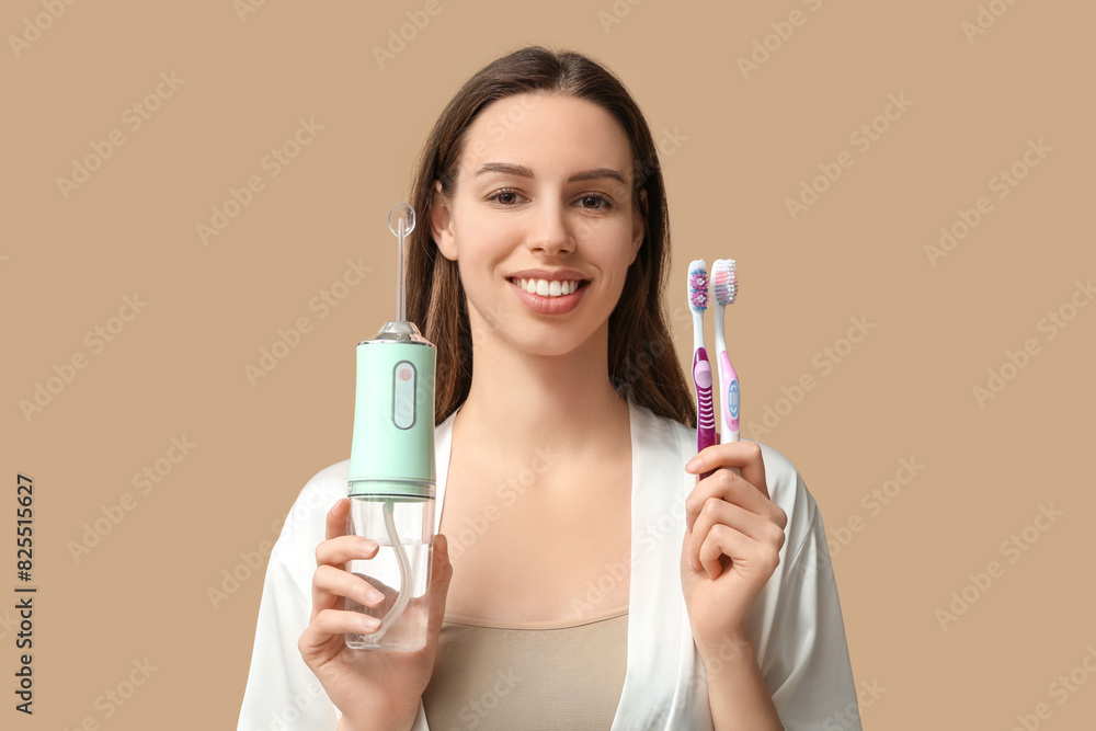 Beautiful young woman with oral irrigator and toothbrushes on brown background Beautiful young woman with oral irrigator and toothbrushes on brown background