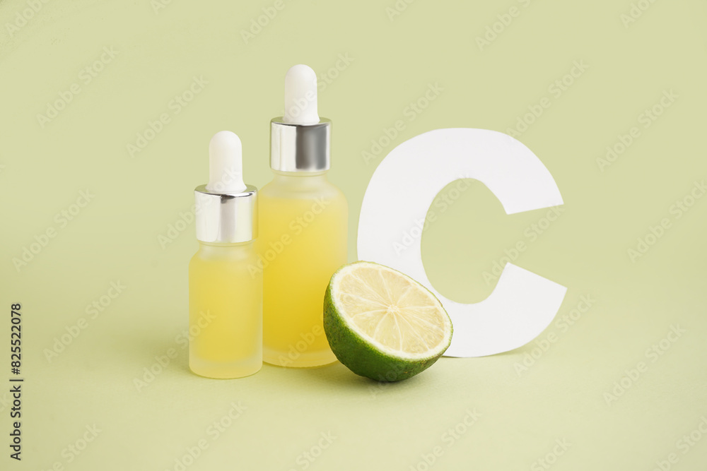 Bottles of citrus essential oil and paper letter C on color background Bottles of citrus essential oil and paper letter C on color background