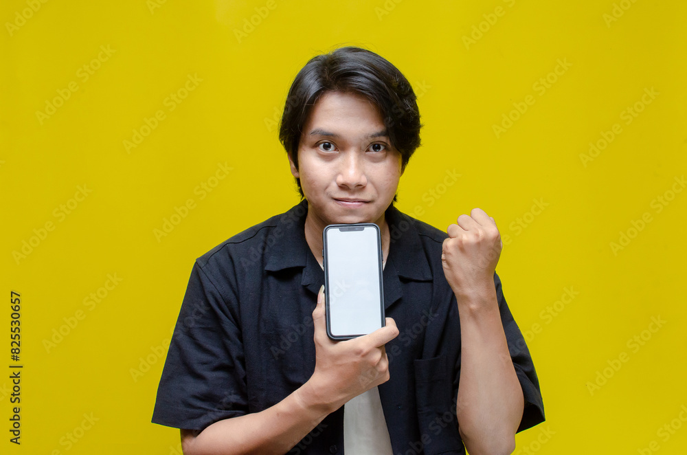 mock up young Asian man showing and pointing at blank screen smartphone. asian man in beige tshirt holding and showing phone screen with happy euphoric shocked wow expression. mock up young Asian man showing and pointing at blank screen smartphone. asian man in beige tshirt holding and showing phone screen with happy euphoric shocked wow expression.