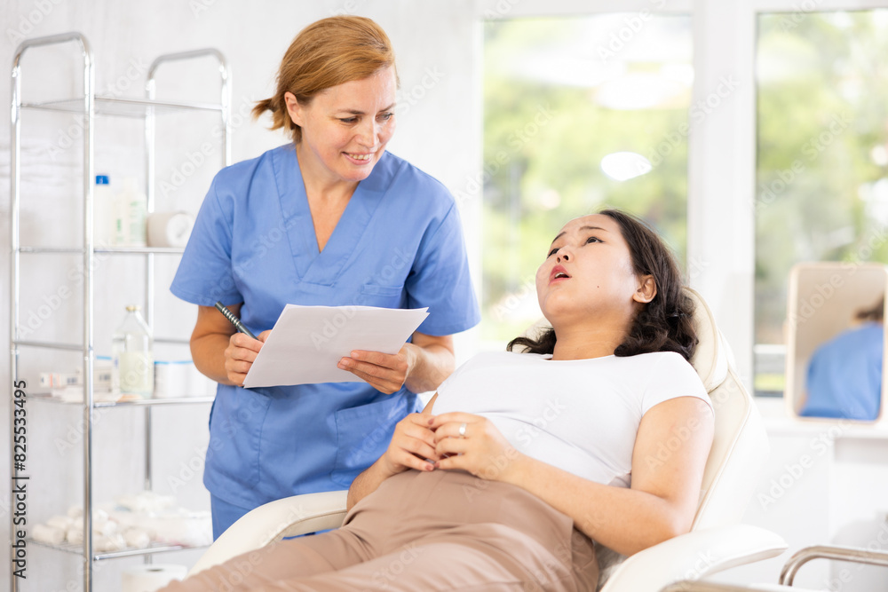 Obraz premium Skilled middle-aged doctor assisting patient in consulting with help of documentation
