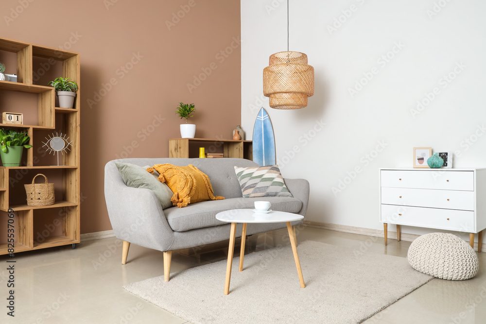 Fototapeta premium Surfboard, cozy sofa and coffee table in beautiful living room