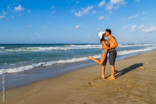 Young couple embracing and kissing at the beach in late summer at dusk.