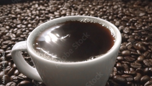 Top view of coffee or espresso with piles of coffee beans. Close up of fresh roasted coffee bean scatter around wooden table with cup of americano and aromatic stream and smoke from seed. Comestible.
