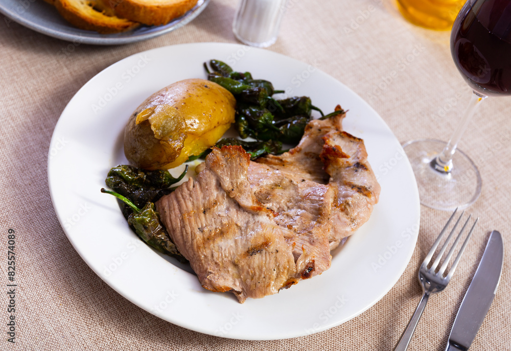 Lunch is beautifully served on plate - fried pork tenderloin, garnished with potatoes baked in peel and pieces of bell pepper.