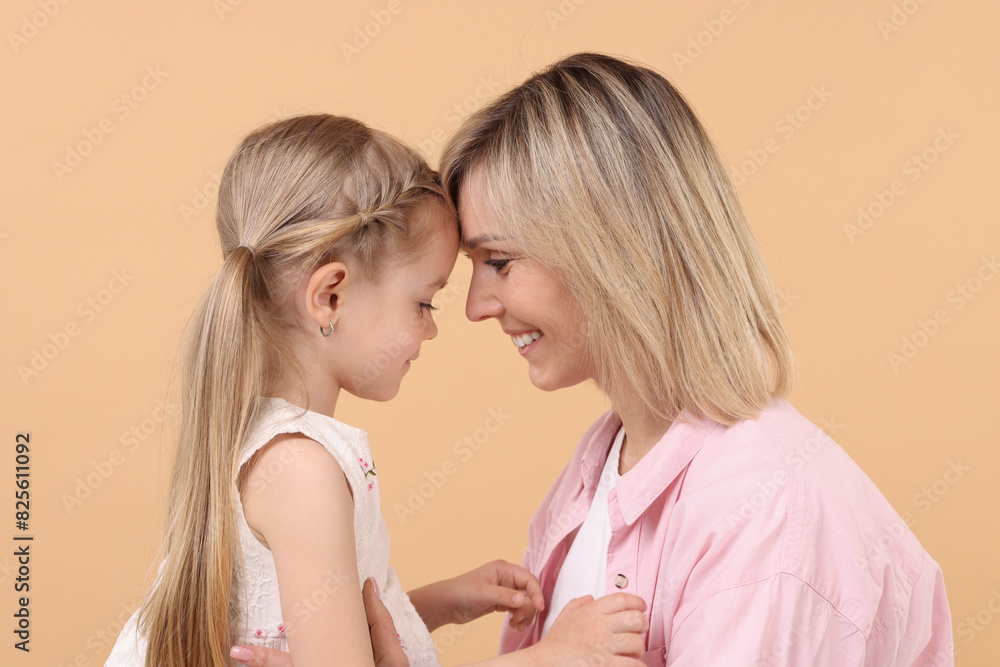 Family portrait of happy mother and daughter on beige background