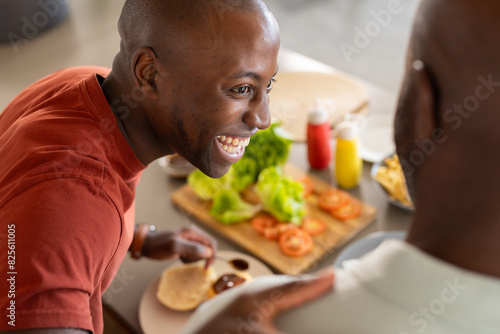 African American father and son in red shirts prepare food at home photo