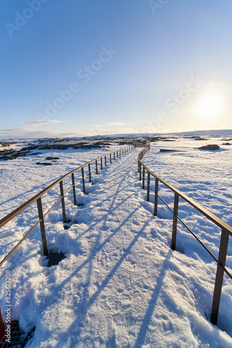 Snow covered metal walkway on sunny day and blue sky