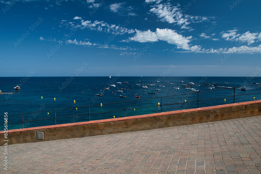 Obraz premium Promenade in Calella de Palafrugell, in the background the sea with boats at anchor. Costa Brava in Catalonia Spain.