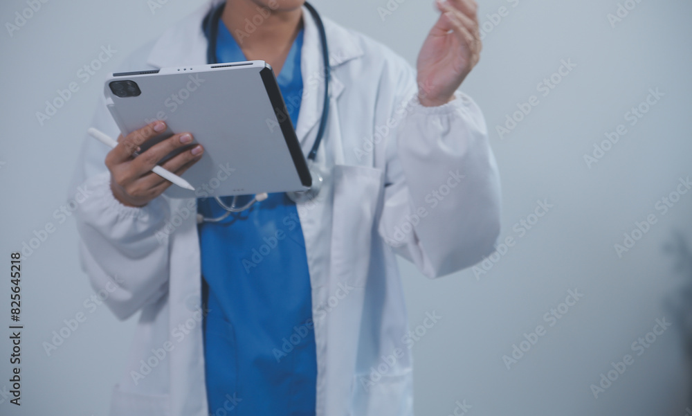 Woman doctor using tablet computer while standing straight in hospital Woman doctor using tablet computer while standing straight in hospital