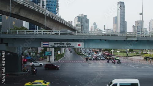 Urban traffic under Thai-Japanese bridge with cars and motorcycles in Bangkok photo