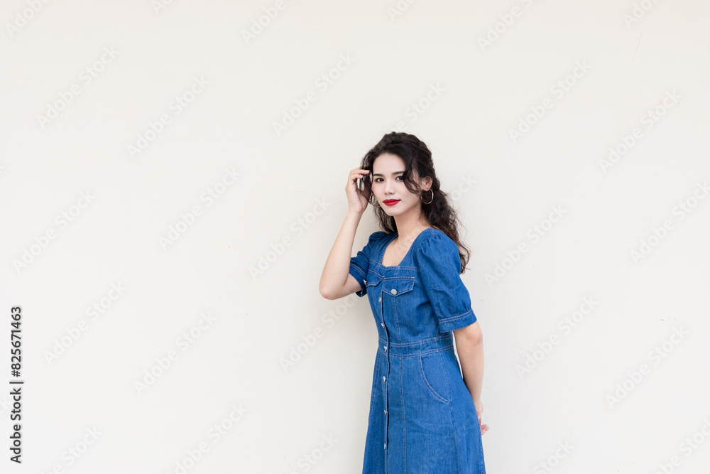 A beautiful woman with curly hair in a denim skirt on a solid background A beautiful woman with curly hair in a denim skirt on a solid background