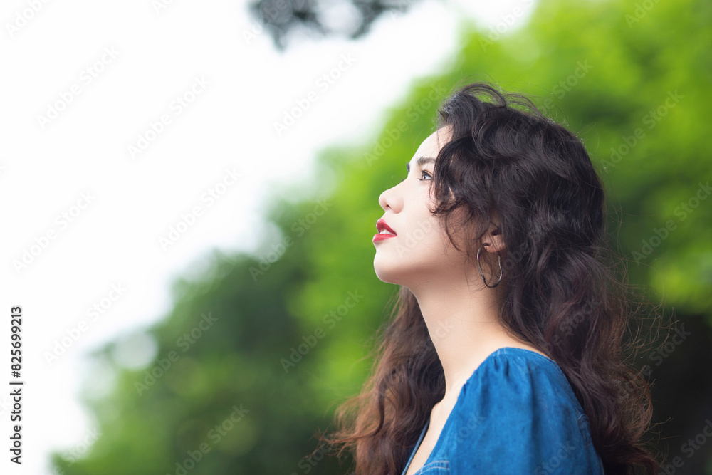 Naklejka premium Outdoors a curly-haired Chinese beauty in a denim skirt