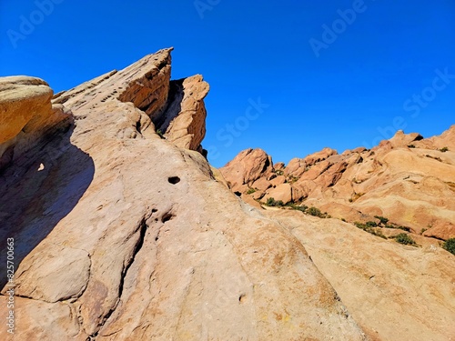 Vasquez Rocks. Jagged rock formations extend under a bright blue sky, offering a glimpse of the rugged beauty of a desert landscape.