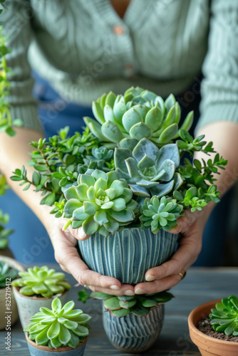 A woman works on an upcycled jar with succulents, surrounded by other plants on the table.
