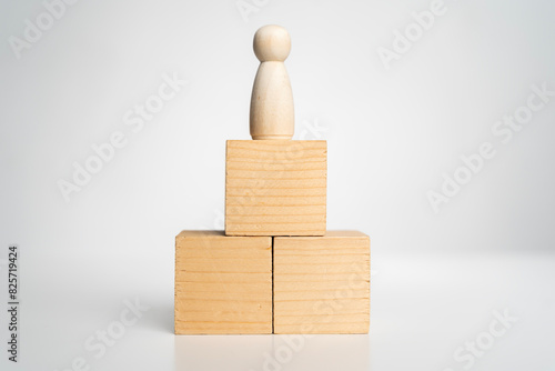 A wooden figure stands on top of three wooden blocks. The blocks are stacked on top of each other.