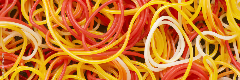 Tangled collection of colorful rubber bands in shades of red, yellow, and white, creating an abstract and chaotic pattern with a playful appearance.