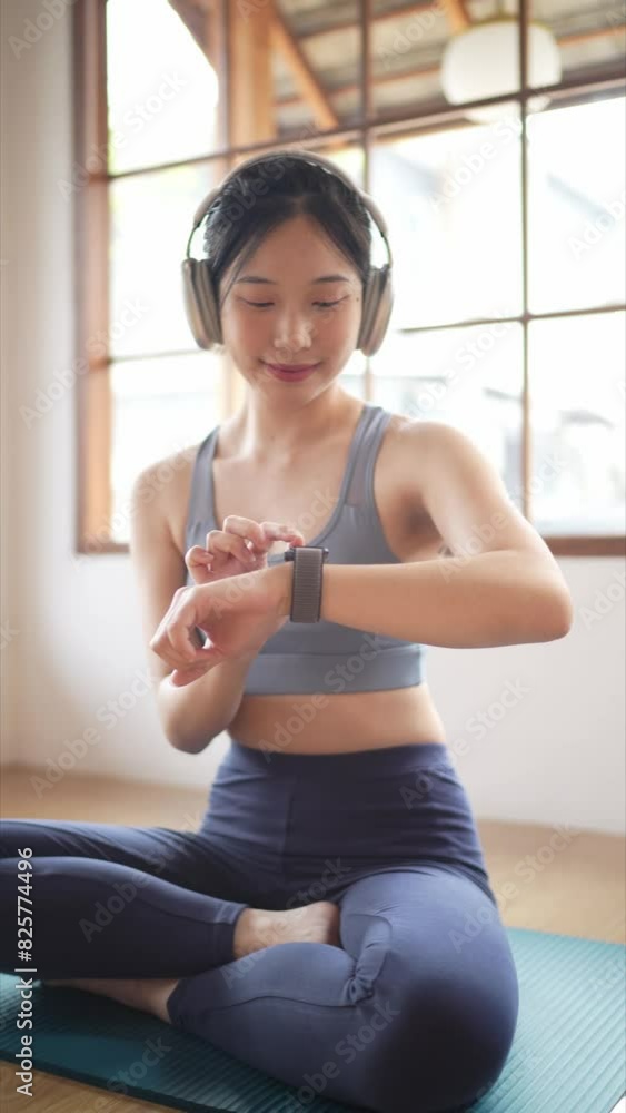 The Asian woman in sportswear is setting up her smartwatch, getting ready for a workout session at her home The Asian woman in sportswear is setting up her smartwatch, getting ready for a workout session at her home