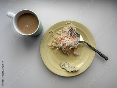 Breakfast is a plate with cabbage, cheese with mold and coffee. Flat Lay