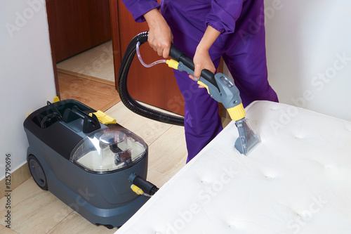 A person is cleaning a mattress with a steam cleaner